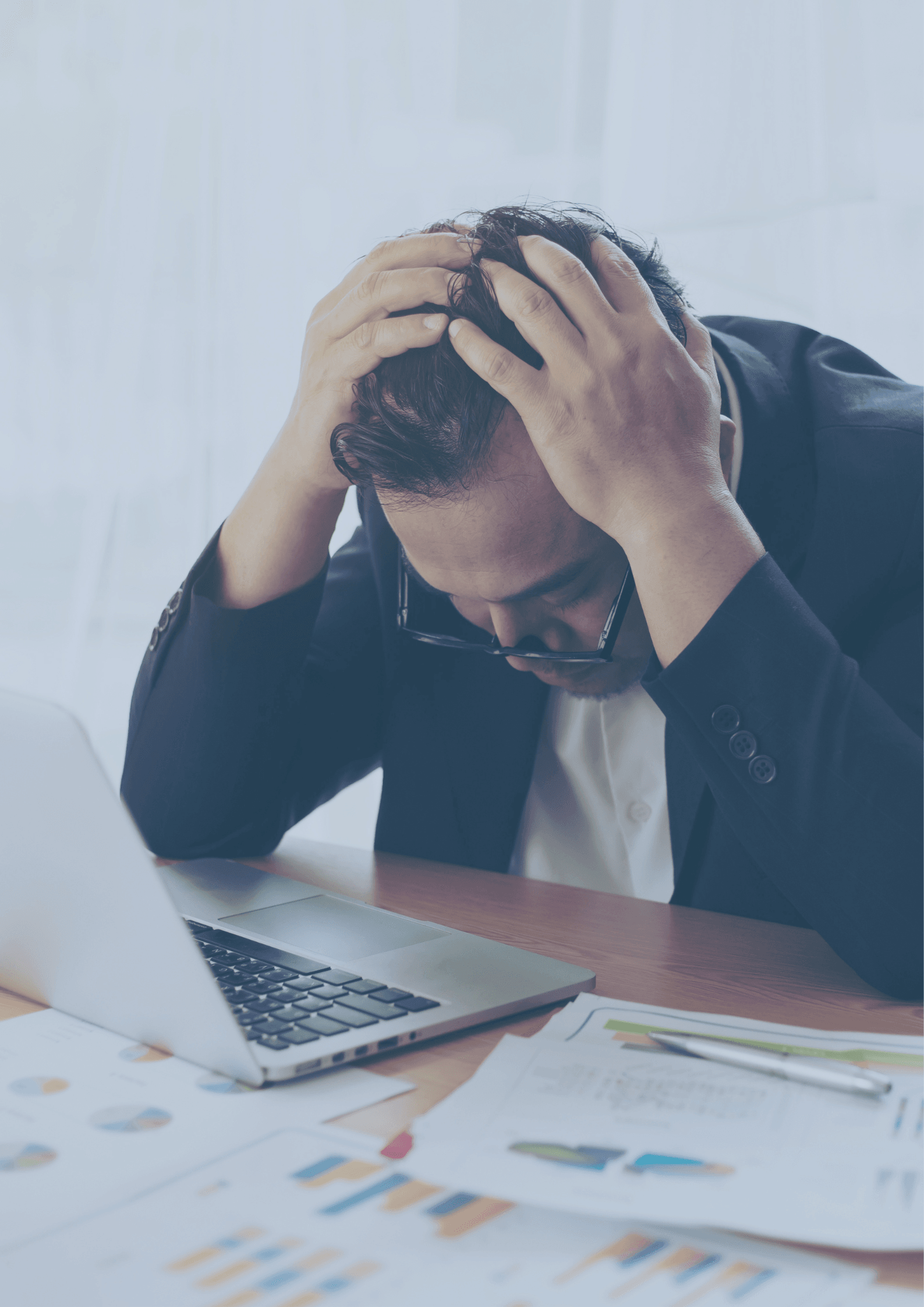 Ejerleder sidder ved skrivebord med regnskabsdokumenter og laptop og oplever manglende overblik over virksomhedens økonomi Ejerleder sidder ved skrivebord med regnskabsdokumenter og laptop og oplever manglende overblik over virksomhedens økonomi